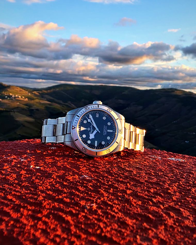 Templário num muro vermelho, com o céu azul e as serras ao fundo.