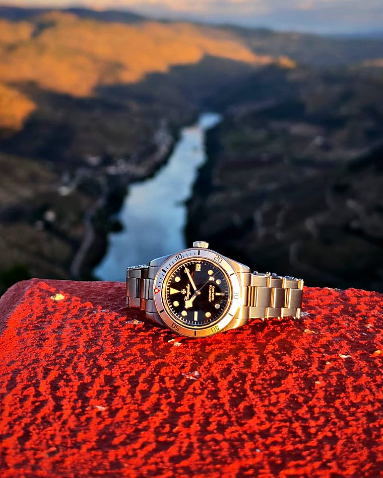 Templário num muro vermelho, por cima de um vale com um rio.